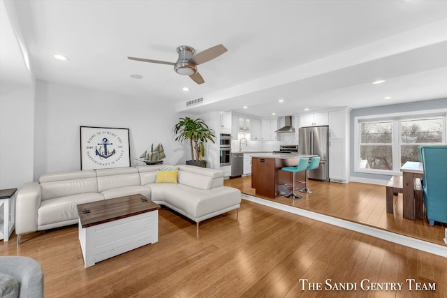 living room with light hardwood / wood-style floors, ceiling fan, and sink