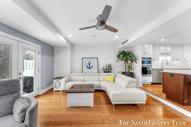 living room with ceiling fan, light hardwood / wood-style floors, and french doors