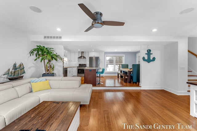 living room with light hardwood / wood-style flooring, ceiling fan, and sink