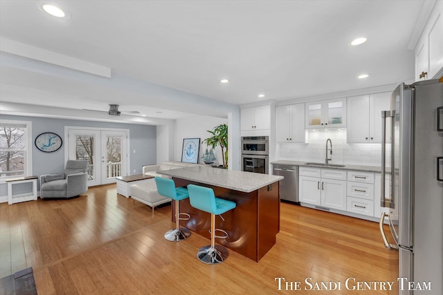 kitchen with white cabinetry, french doors, a breakfast bar area, a kitchen island, and appliances with stainless steel finishes