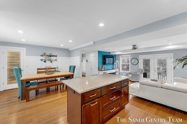 kitchen featuring ceiling fan, a center island, light wood-type flooring, and french doors