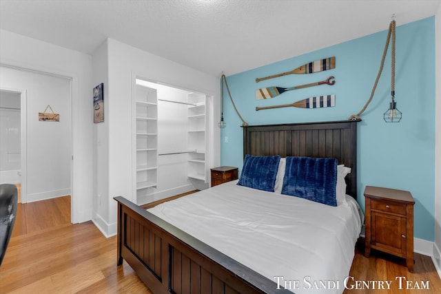 bedroom with a walk in closet, a closet, and light hardwood / wood-style floors