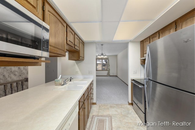 kitchen featuring light carpet, appliances with stainless steel finishes, decorative light fixtures, and sink