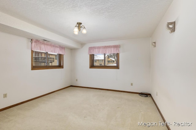 spare room with a textured ceiling and light colored carpet