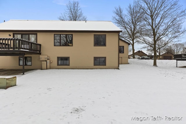 snow covered rear of property with a deck