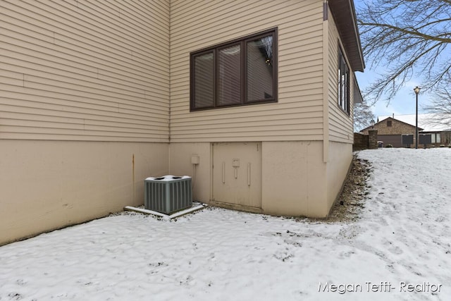 snow covered property with central air condition unit