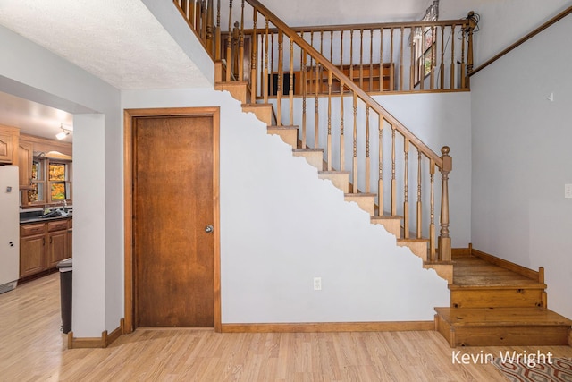 stairway with hardwood / wood-style floors and a textured ceiling