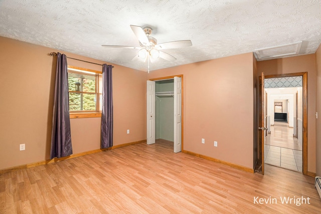 unfurnished bedroom with ceiling fan, a baseboard radiator, light hardwood / wood-style floors, a textured ceiling, and a closet