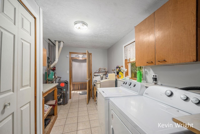 washroom with separate washer and dryer, light tile patterned floors, cabinets, and a textured ceiling