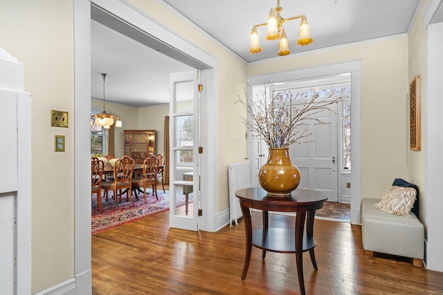 foyer featuring ornamental molding, dark wood-type flooring, and an inviting chandelier