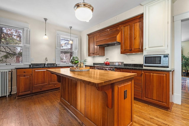 kitchen featuring a kitchen island, radiator, sink, wooden counters, and light hardwood / wood-style floors