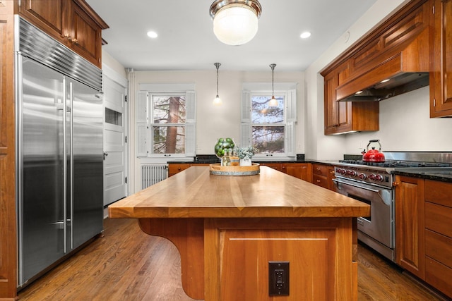 kitchen with butcher block countertops, premium appliances, dark hardwood / wood-style flooring, a kitchen island, and pendant lighting