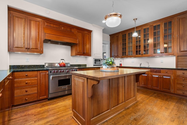 kitchen with a kitchen island, appliances with stainless steel finishes, wood counters, hardwood / wood-style flooring, and custom range hood