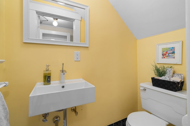 bathroom featuring sink, vaulted ceiling, and toilet