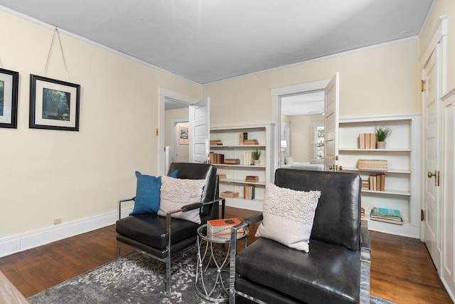 living area with built in shelves, ornamental molding, and dark hardwood / wood-style floors