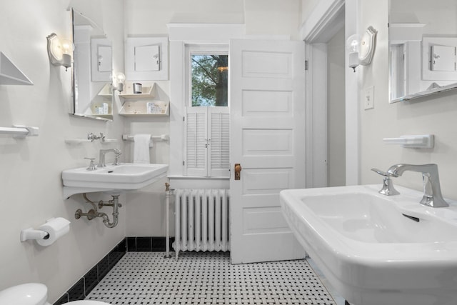 bathroom featuring dual sinks and radiator