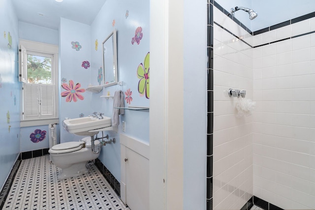 bathroom with a tile shower and toilet