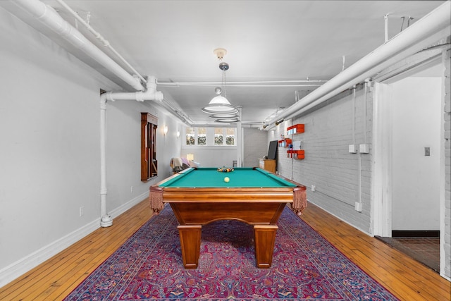 recreation room with hardwood / wood-style flooring, billiards, and brick wall