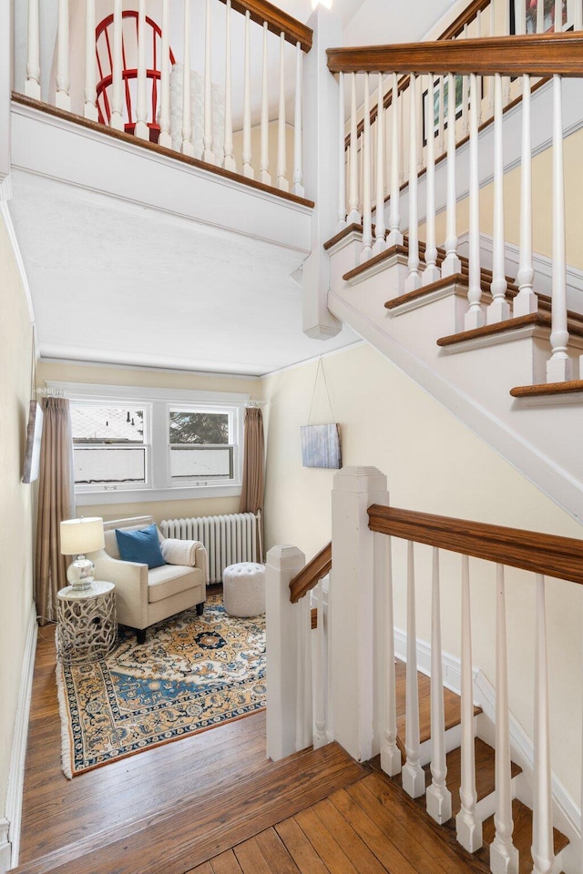 stairs featuring hardwood / wood-style floors and radiator heating unit