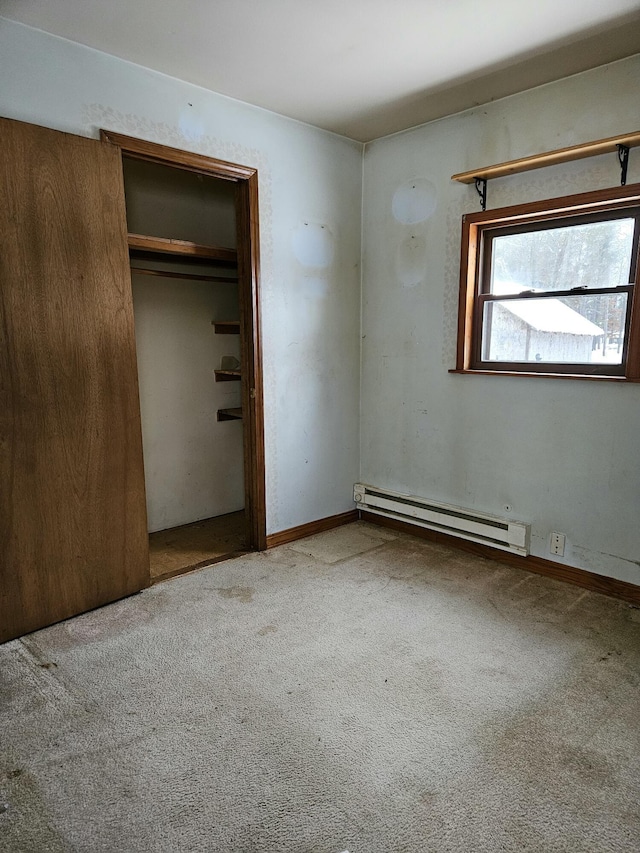 unfurnished bedroom with a closet, carpet floors, and a baseboard heating unit