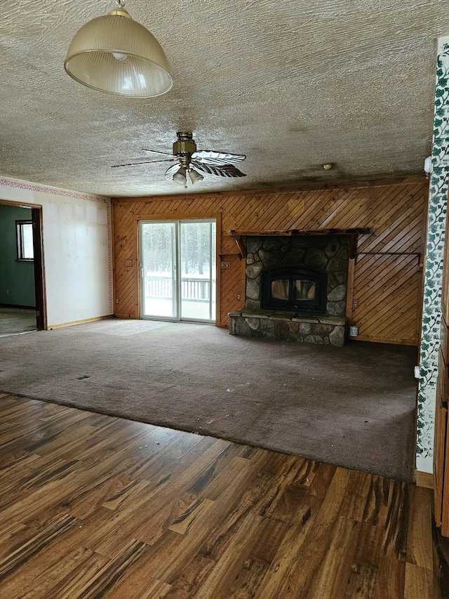 unfurnished living room with carpet flooring, a stone fireplace, and ceiling fan