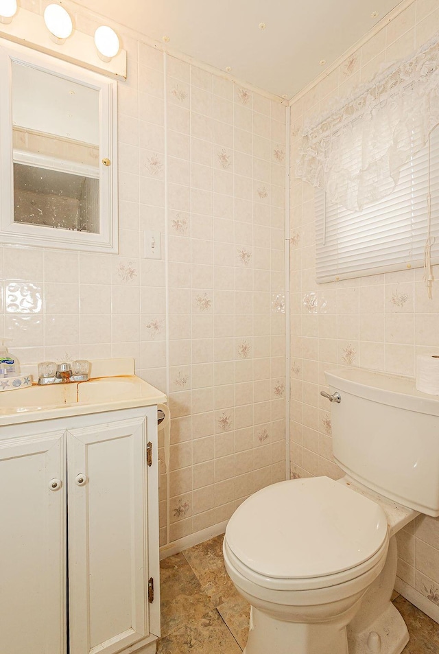 bathroom with vanity, toilet, and tile walls