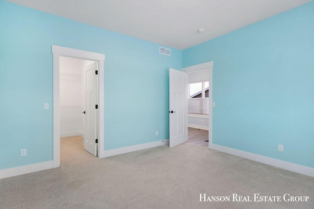 unfurnished bedroom with light colored carpet, a spacious closet, and a closet