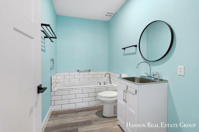 bathroom with vanity, a relaxing tiled tub, wood-type flooring, and toilet