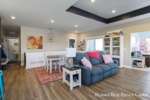 living room with hardwood / wood-style floors and a raised ceiling