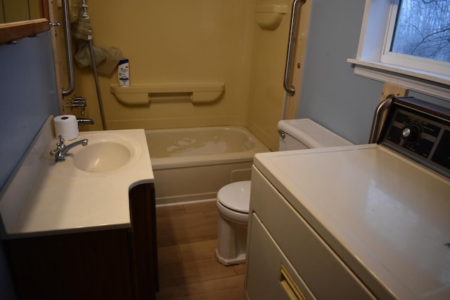 bathroom featuring hardwood / wood-style flooring, toilet, vanity, and washer / dryer