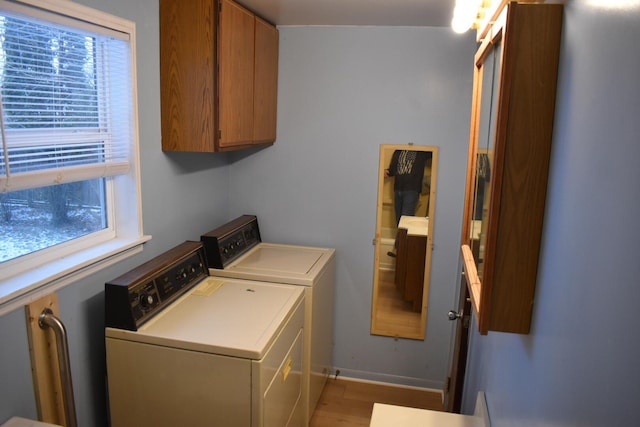 clothes washing area featuring cabinets, light wood-type flooring, and independent washer and dryer