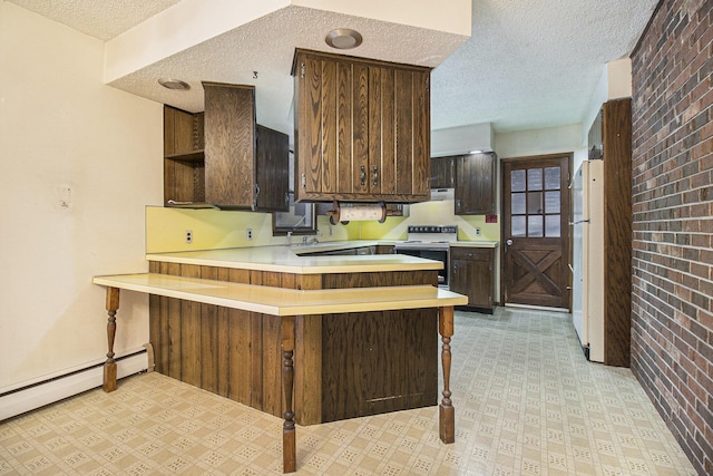 kitchen with dark brown cabinetry, baseboard heating, brick wall, kitchen peninsula, and white appliances