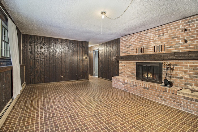 unfurnished living room with wooden walls, a textured ceiling, and a brick fireplace