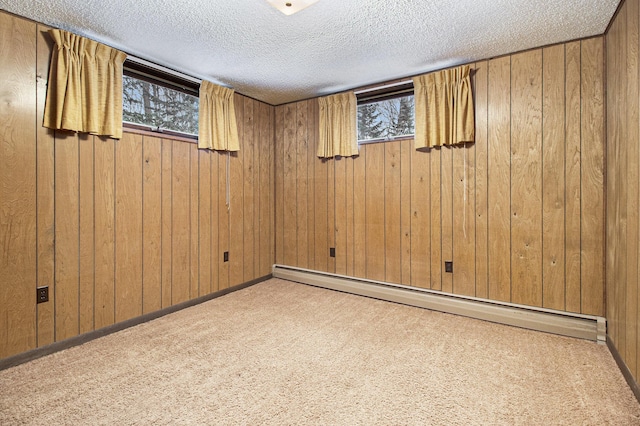 empty room featuring wooden walls, light colored carpet, a baseboard radiator, and a textured ceiling