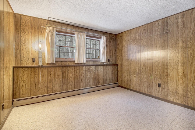 unfurnished room featuring wood walls, light carpet, a textured ceiling, and a baseboard heating unit