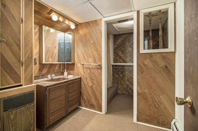 bathroom with wood walls, vanity, and a baseboard heating unit