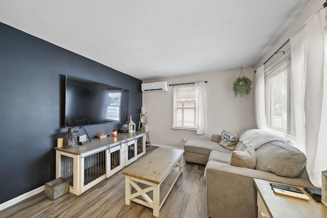 living room with hardwood / wood-style flooring, an AC wall unit, and a wealth of natural light