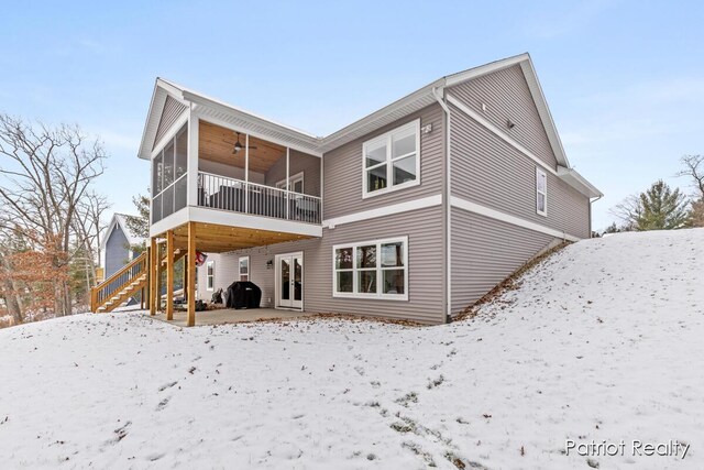 snow covered house with ceiling fan and a sunroom