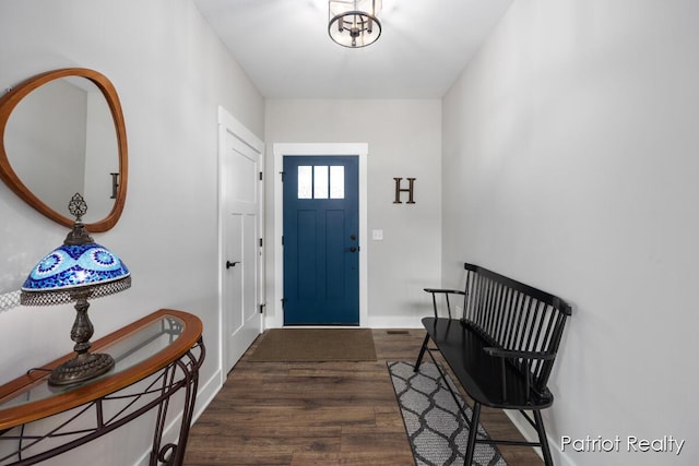 entryway with dark wood-type flooring and an inviting chandelier