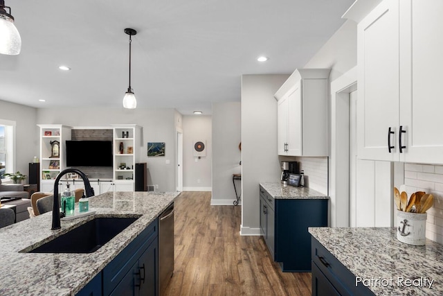 kitchen featuring tasteful backsplash, decorative light fixtures, sink, blue cabinetry, and white cabinets