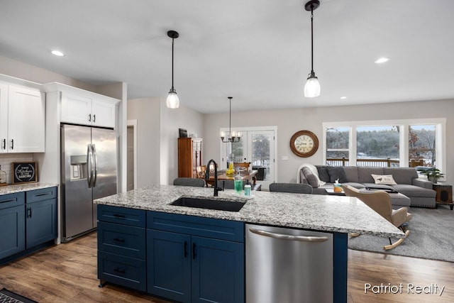 kitchen featuring white cabinetry, stainless steel appliances, decorative light fixtures, blue cabinets, and sink