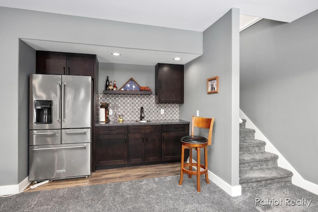 kitchen featuring high end refrigerator, tasteful backsplash, sink, carpet flooring, and dark brown cabinets