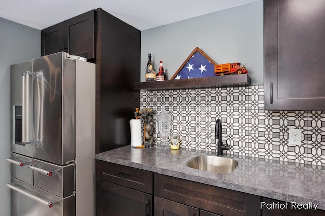 kitchen with backsplash, sink, high quality fridge, and dark brown cabinetry