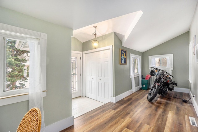 foyer entrance featuring lofted ceiling, dark wood-type flooring, and a wealth of natural light