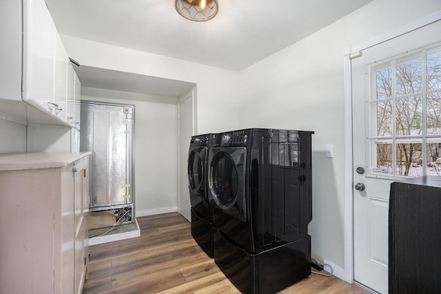 washroom with cabinets, wood-type flooring, and washer and clothes dryer