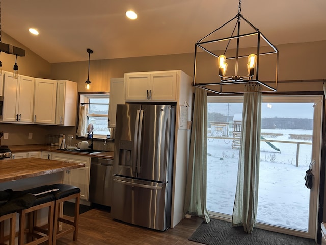 kitchen with appliances with stainless steel finishes, sink, butcher block countertops, white cabinetry, and hanging light fixtures