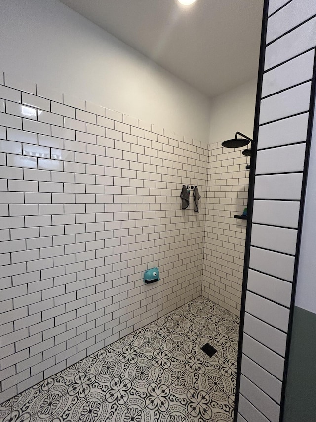 bathroom with tiled shower and tile patterned flooring