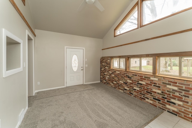 foyer featuring high vaulted ceiling, ceiling fan, light colored carpet, and brick wall