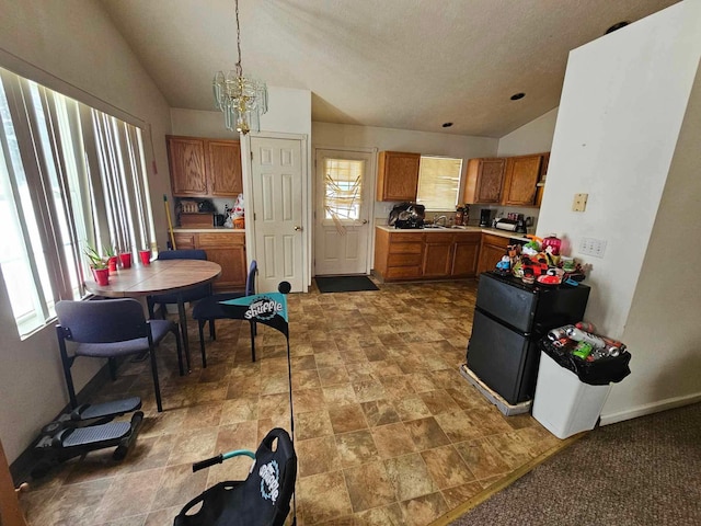 kitchen with decorative light fixtures, black refrigerator, a chandelier, and lofted ceiling