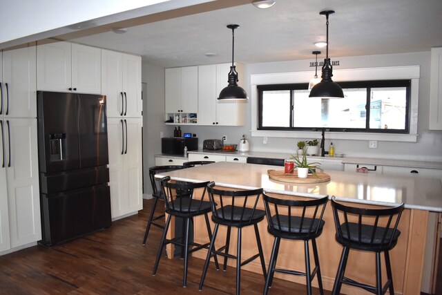 kitchen with dark hardwood / wood-style flooring, white cabinetry, fridge with ice dispenser, and a breakfast bar